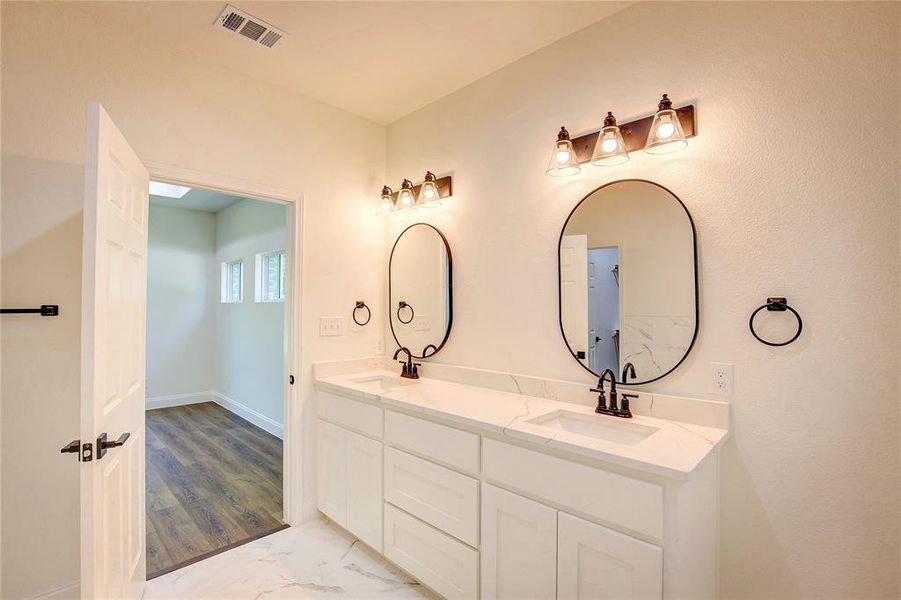 Full bathroom featuring double vanity and marble finish flooring Full bathroom featuring double vanity and marble finish flooring