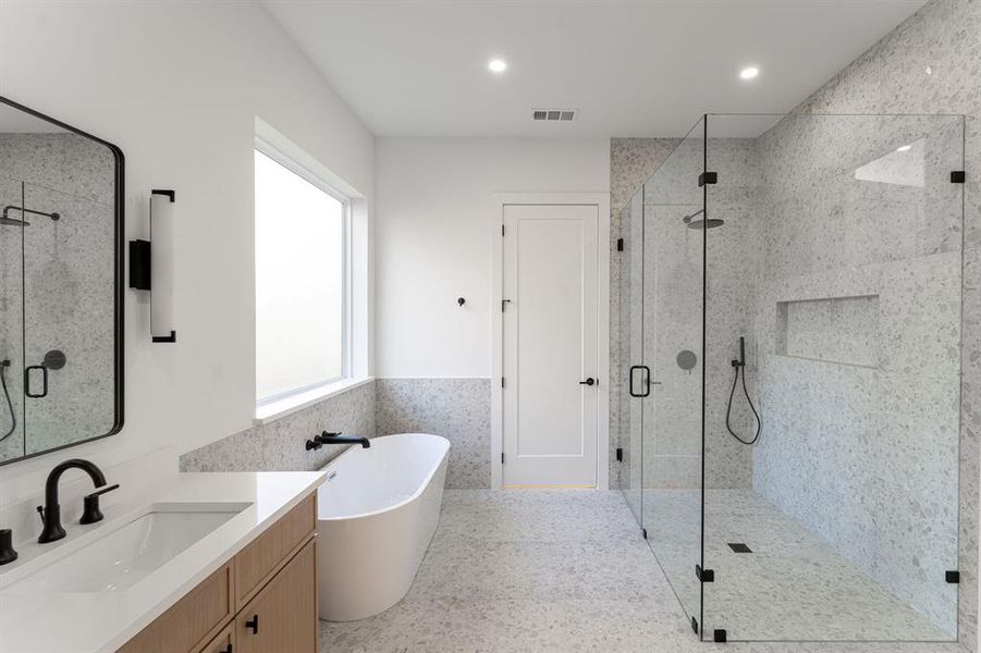 Bathroom featuring separate shower and tub, vanity, and tile walls