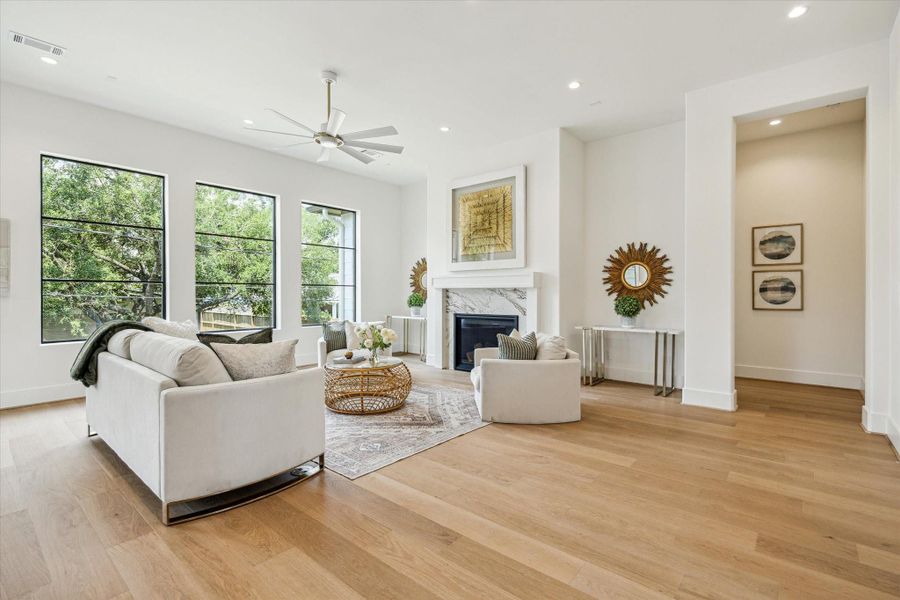 Living room is spacious with lots of art walls and features a gas fireplace with modern mantle and porcelain surround.