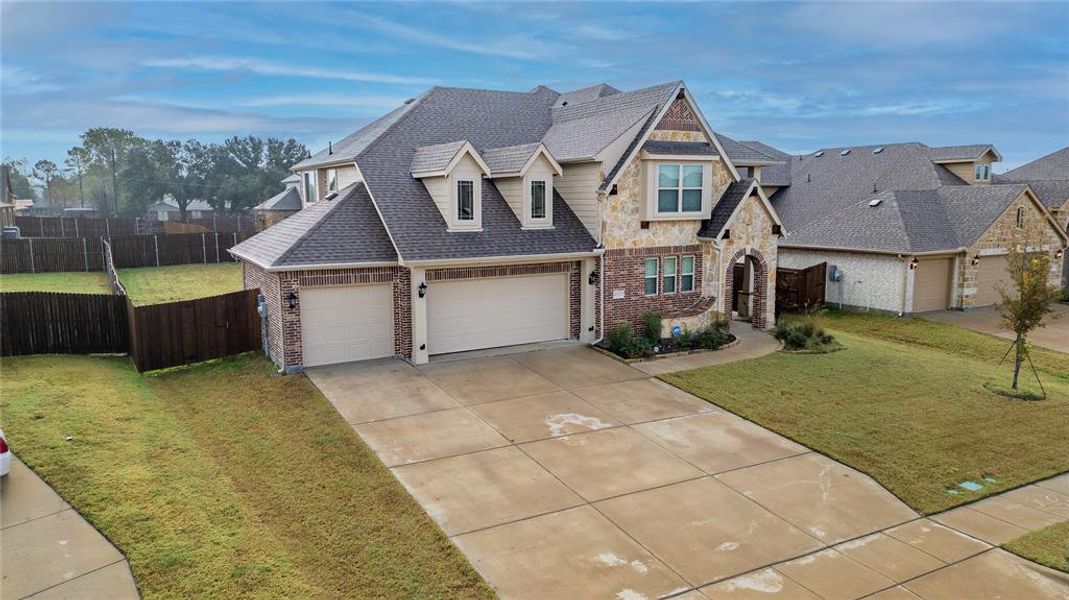 View of front of property with a shingled roof, driveway, brick siding, and stone siding View of front of property with a shingled roof, driveway, brick siding, and stone siding