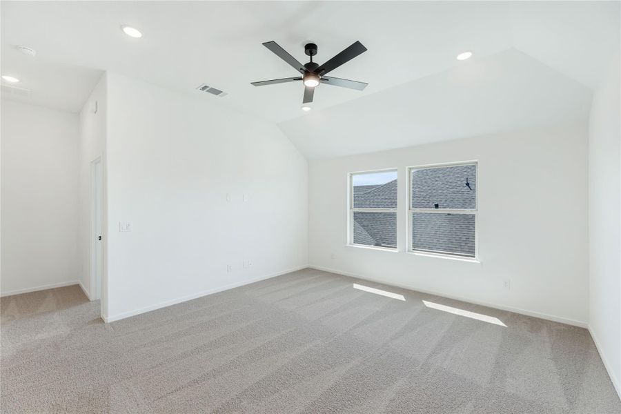 Empty bedroom with vaulted ceiling, ceiling fan, carpet flooring, and a double window