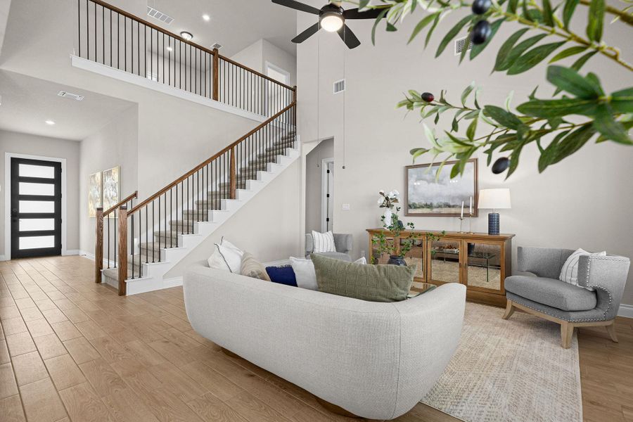Living room featuring a towering ceiling, light wood-type flooring, stairway, recessed lighting, and ceiling fan