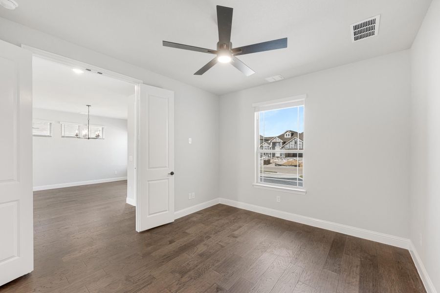 Empty bedroom with dark hardwood floors, ceiling fan, and window overlooking neighborhood Empty bedroom with dark hardwood floors, ceiling fan, and window overlooking neighborhood
