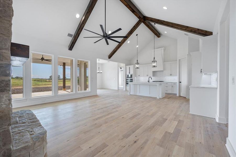 Living room with a ceiling fan, high vaulted ceiling, beamed ceiling, a sink, and light wood-type flooring Living room with a ceiling fan, high vaulted ceiling, beamed ceiling, a sink, and light wood-type flooring