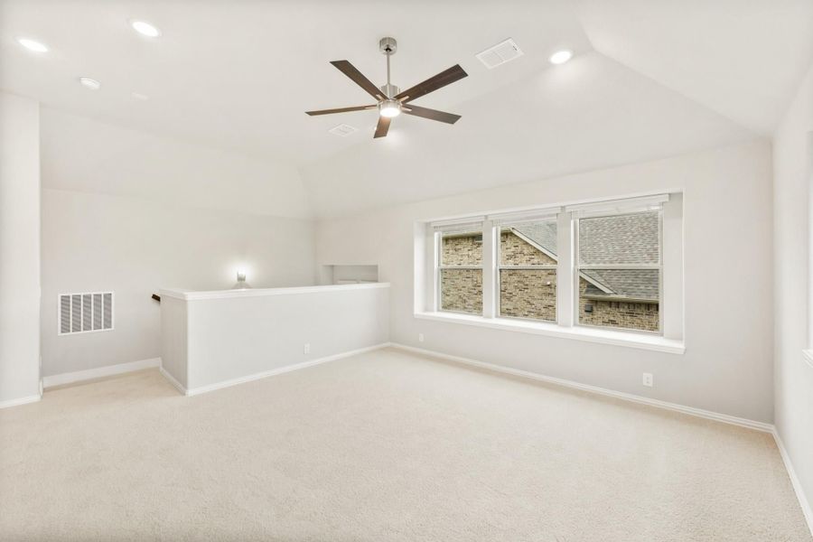Empty living room with vaulted ceiling, ceiling fan, carpet flooring, and large window Empty living room with vaulted ceiling, ceiling fan, carpet flooring, and large window