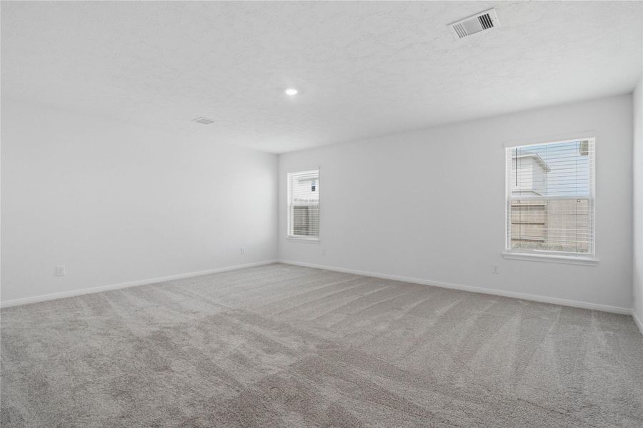 Unwind after a long day in this stunning primary suite! This spacious retreat features plush carpeting, neutral-toned walls, soaring ceilings, recessed lighting, and large windows with privacy blinds for comfort and tranquility.