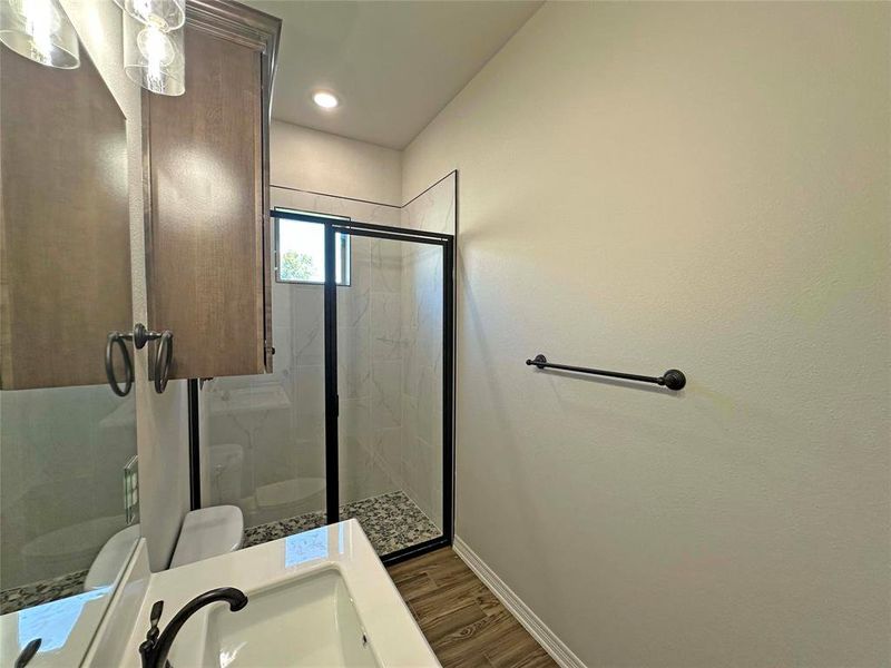 Full bathroom with vanity, wood finished floors, a marble finish shower, and recessed lighting Full bathroom with vanity, wood finished floors, a marble finish shower, and recessed lighting