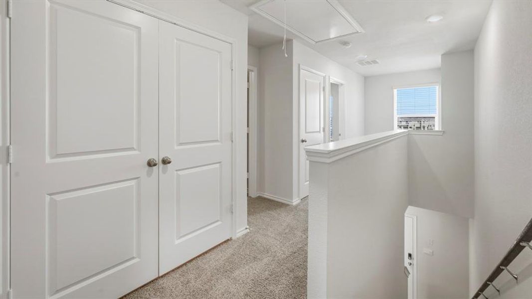 Corridor with attic access, light carpet, and an upstairs landing