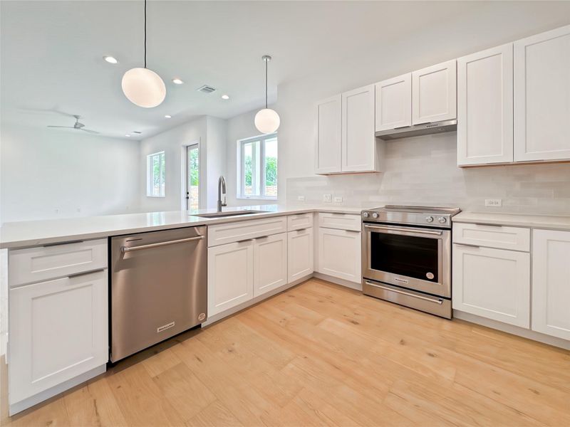 Kitchen featuring stainless steel appliances, light countertops, white cabinets, and decorative backsplash Kitchen featuring stainless steel appliances, light countertops, white cabinets, and decorative backsplash