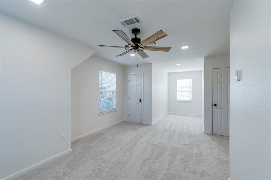 Carpeted empty room featuring ceiling fan