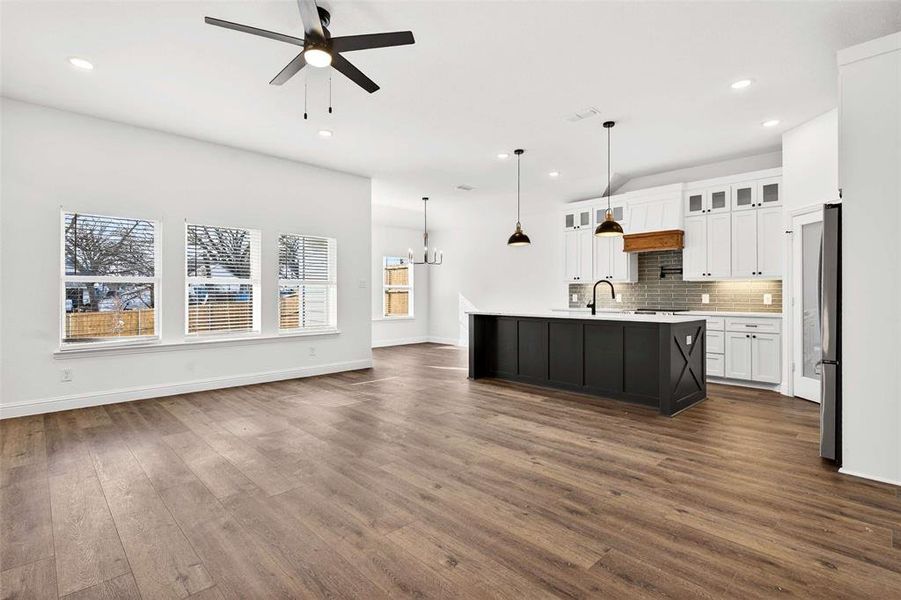 Kitchen featuring glass insert cabinets, white cabinets, open floor plan, an island with sink, and a chandelier