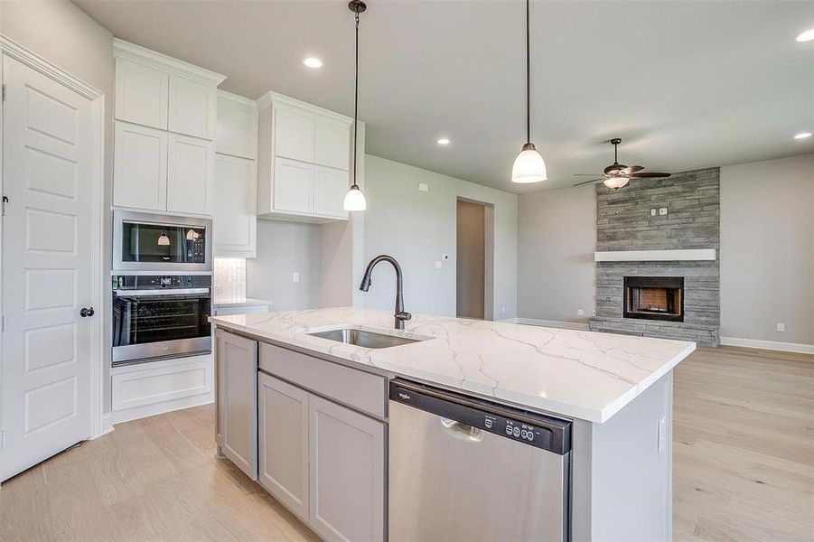 Kitchen featuring appliances with stainless steel finishes, white cabinetry, ceiling fan, a center island with sink, and sink