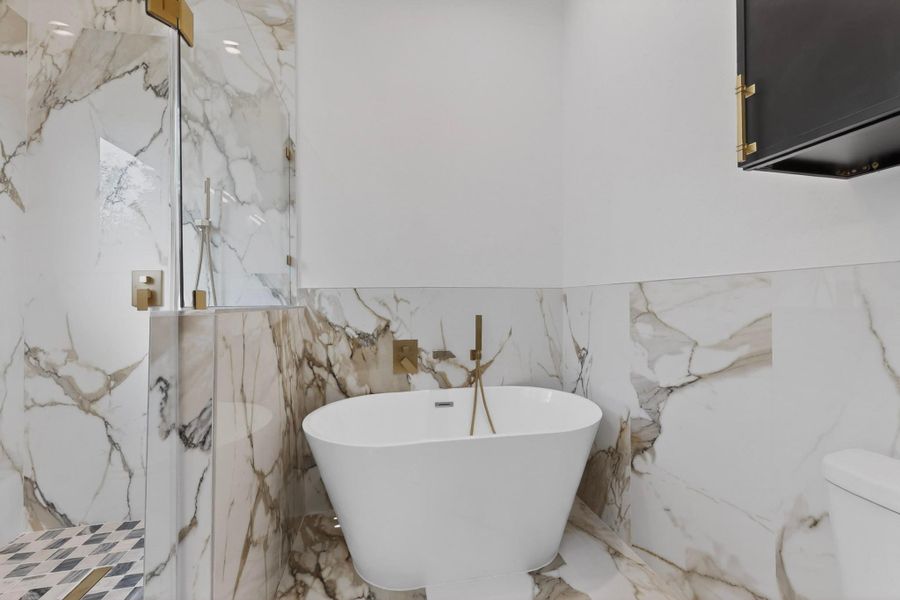 Luxurious marble surrounds a freestanding soaking tub and a sleek glass-enclosed shower, creating a serene spa-like retreat.