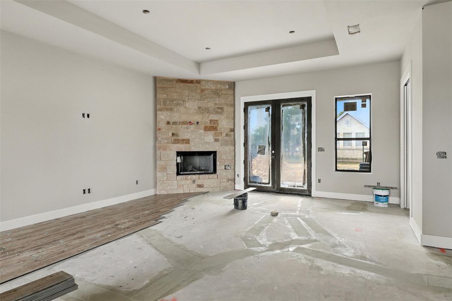 Unfurnished living room with a tray ceiling, a tiled fireplace, and french doors Unfurnished living room with a tray ceiling, a tiled fireplace, and french doors