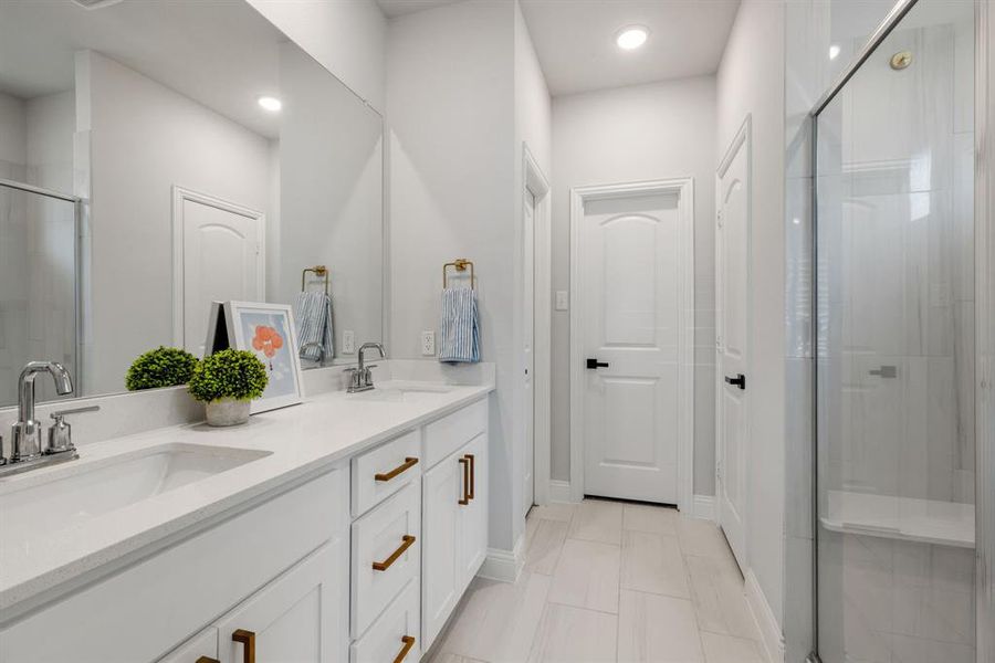 Full bathroom with a shower stall, double vanity, and light tile patterned floors