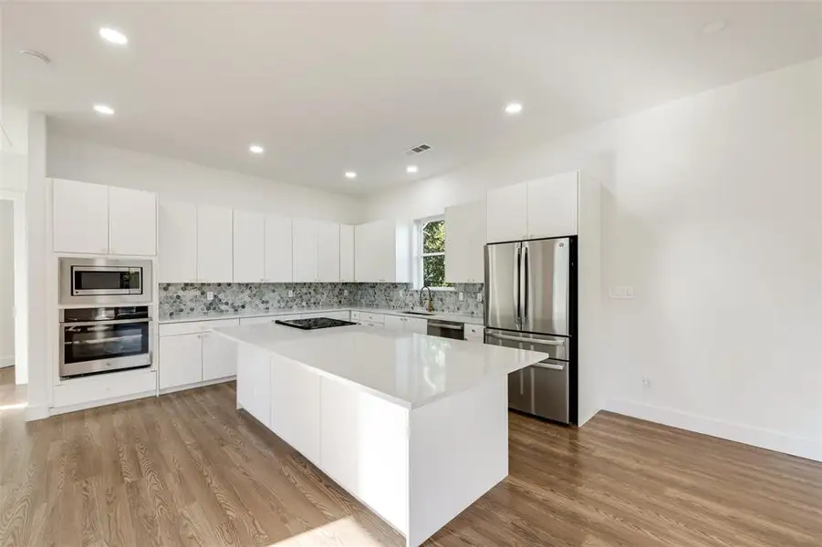 Kitchen with decorative backsplash, white cabinetry, modern cabinets, appliances with stainless steel finishes, and recessed lighting Kitchen with decorative backsplash, white cabinetry, modern cabinets, appliances with stainless steel finishes, and recessed lighting