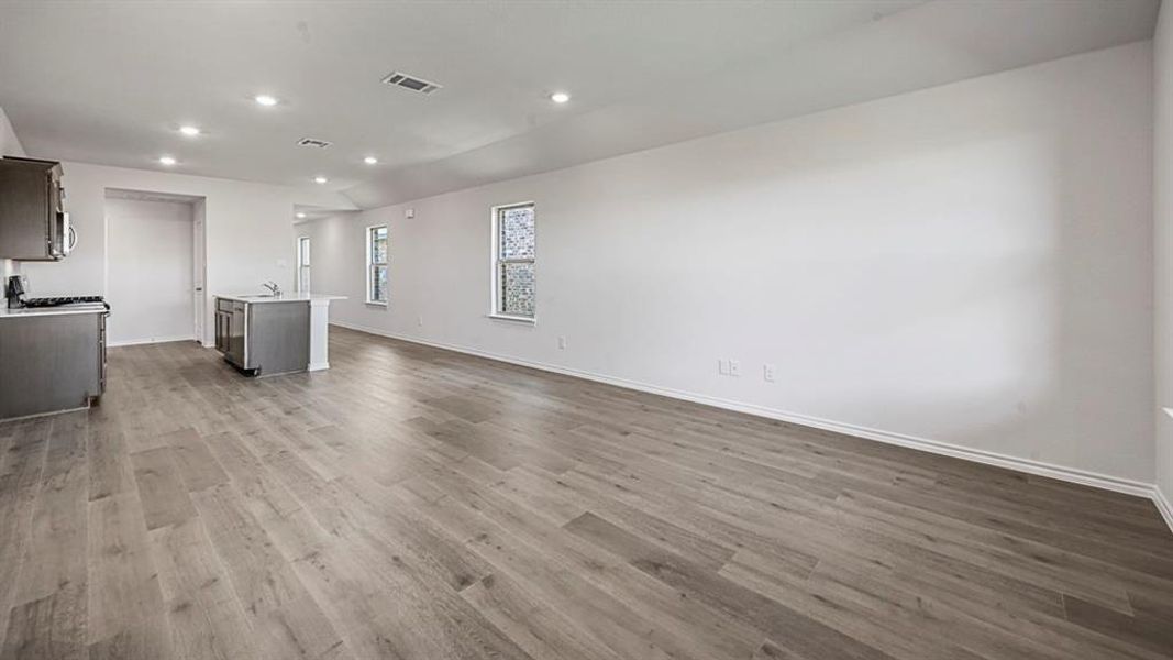 Open-concept living area featuring wood-finish flooring, recessed lighting, and ample natural light from multiple windows