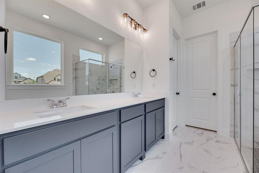 Full bath featuring a marble finish shower, light marble finish floors, and double vanity Full bath featuring a marble finish shower, light marble finish floors, and double vanity