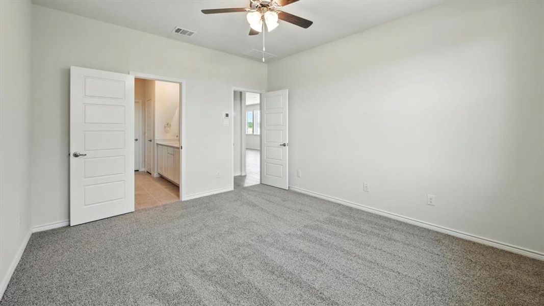 Unfurnished bedroom featuring ensuite bathroom, light carpet, and a ceiling fan