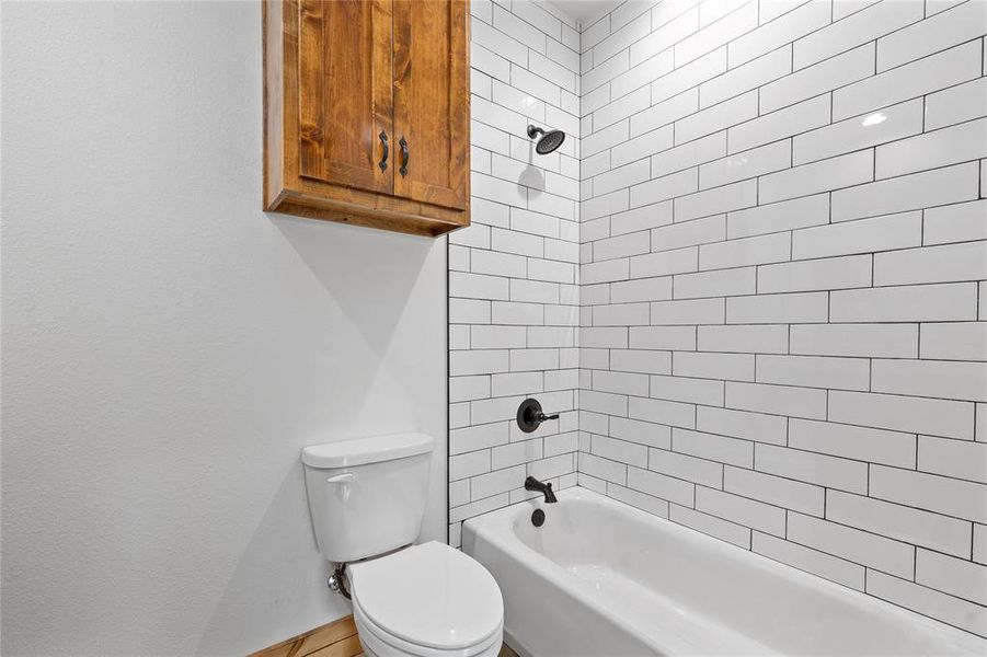 Bathroom featuring toilet, shower combination, and baseboards Bathroom featuring toilet, shower combination, and baseboards