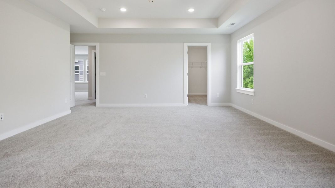 Bedroom with tray ceiling, window, and access to closet and loft area Bedroom with tray ceiling, window, and access to closet and loft area