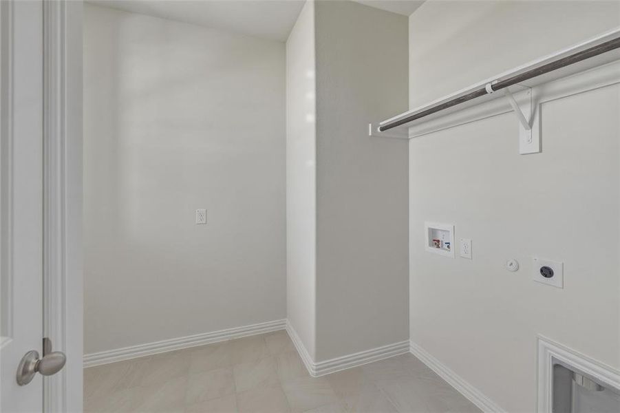 Dedicated utility area featuring tile flooring, neutral wall tones, and baseboard trim Dedicated utility area featuring tile flooring, neutral wall tones, and baseboard trim