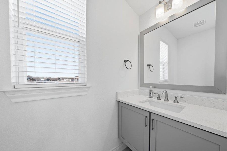 An elegant stone counter highlights this modern vanity area illuminated by natural light. An elegant stone counter highlights this modern vanity area illuminated by natural light.