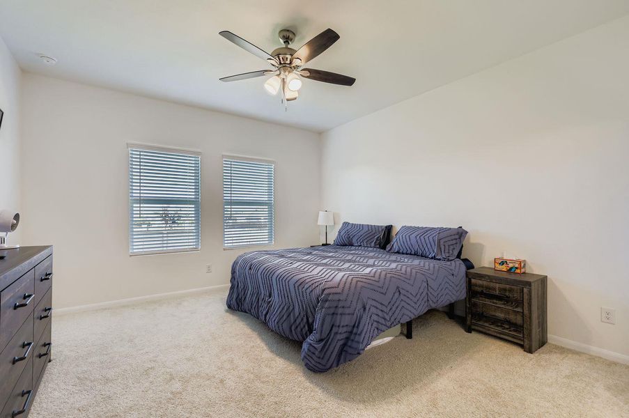 Bedroom with light colored carpet and a ceiling fan