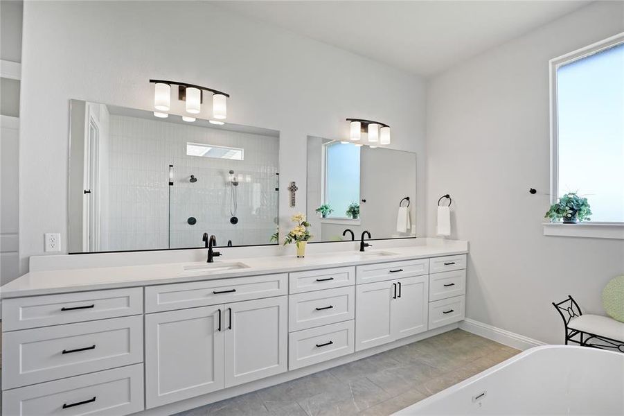 Bathroom featuring a shower stall, a freestanding bath, double vanity, and baseboards Bathroom featuring a shower stall, a freestanding bath, double vanity, and baseboards