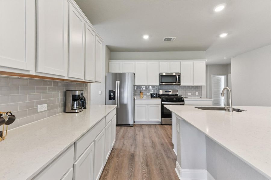 Kitchen featuring stainless steel appliances, tasteful backsplash, light wood finished floors, white cabinets, and recessed lighting Kitchen featuring stainless steel appliances, tasteful backsplash, light wood finished floors, white cabinets, and recessed lighting
