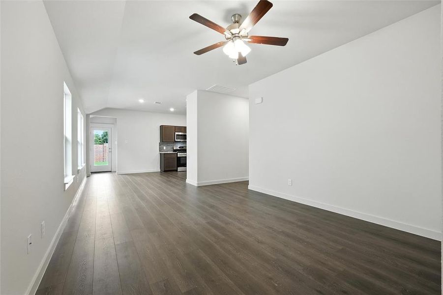 Unfurnished living room with vaulted ceiling, dark wood-style flooring, ceiling fan, and recessed lighting Unfurnished living room with vaulted ceiling, dark wood-style flooring, ceiling fan, and recessed lighting