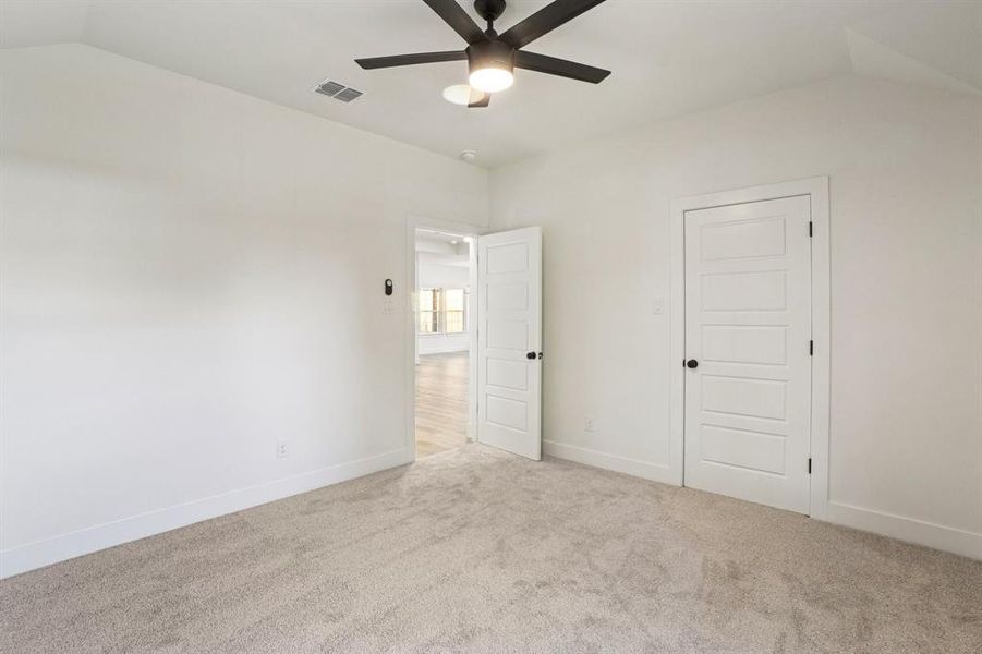 Unfurnished bedroom with carpet floors, vaulted ceiling, and ceiling fan Unfurnished bedroom with carpet floors, vaulted ceiling, and ceiling fan
