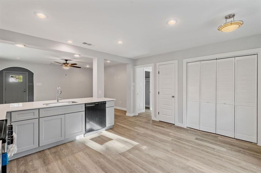 Kitchen with black dishwasher, sink, light wood-type flooring, and ceiling fan