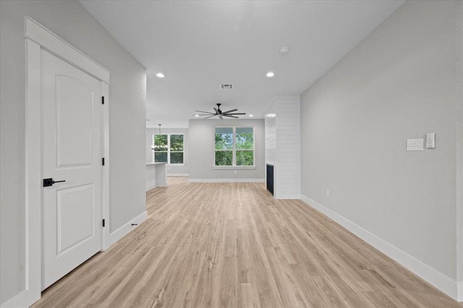 Unfurnished living room with light wood-style floors, recessed lighting, a ceiling fan, and a large fireplace