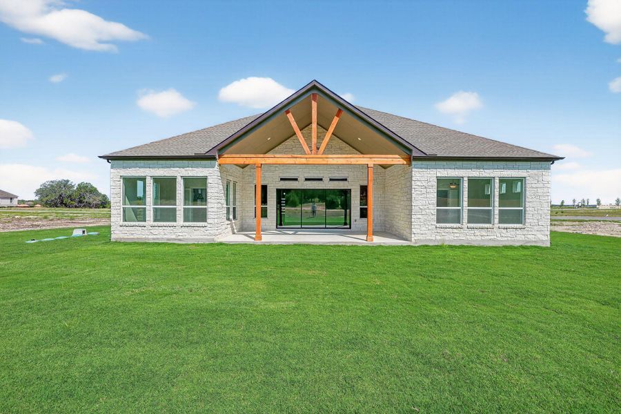 Back of property with a patio, a yard, stone siding, and brick siding Back of property with a patio, a yard, stone siding, and brick siding