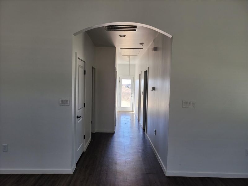 A graceful arched doorway ushers you into a sun-drenched hallway, featuring rich wood flooring. A graceful arched doorway ushers you into a sun-drenched hallway, featuring rich wood flooring.