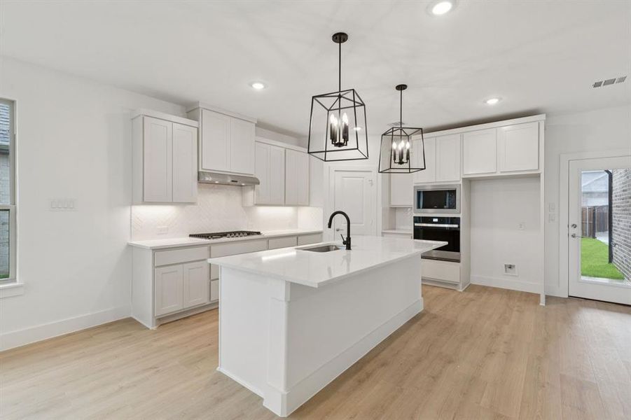 Kitchen featuring oven, stainless steel microwave, decorative backsplash, light wood-style flooring, and recessed lighting Kitchen featuring oven, stainless steel microwave, decorative backsplash, light wood-style flooring, and recessed lighting