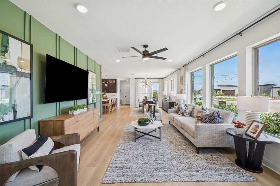 Open-concept living space with light wood-finish flooring, recessed ceiling lighting, and a modern ceiling fan
