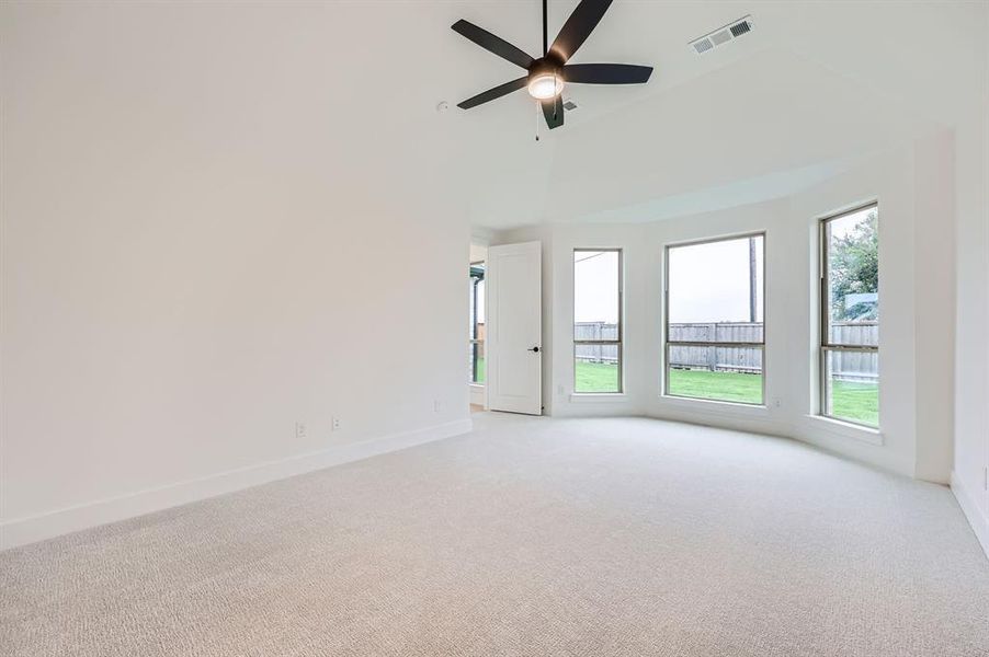 Spare room featuring a towering ceiling, light colored carpet, and ceiling fan