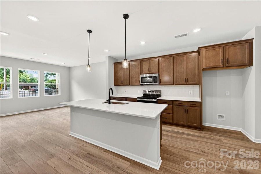 Kitchen with warm brown cabinets paired with white quartz countertops Kitchen with warm brown cabinets paired with white quartz countertops