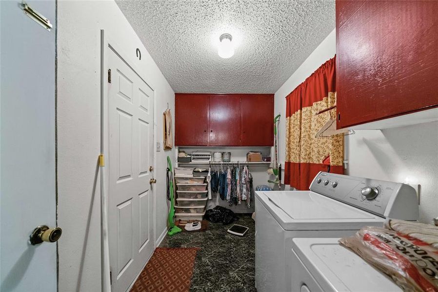 Laundry area featuring independent washer and dryer, a textured ceiling, and cabinet space