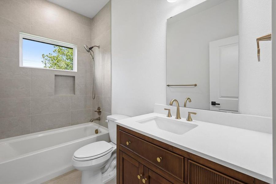 Full bathroom featuring tiled shower / bath combo, vanity, and toilet