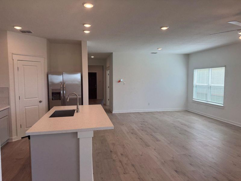 Kitchen with recessed lighting, stainless steel fridge with ice dispenser, light wood-style floors, an island with sink, and open floor plan Kitchen with recessed lighting, stainless steel fridge with ice dispenser, light wood-style floors, an island with sink, and open floor plan