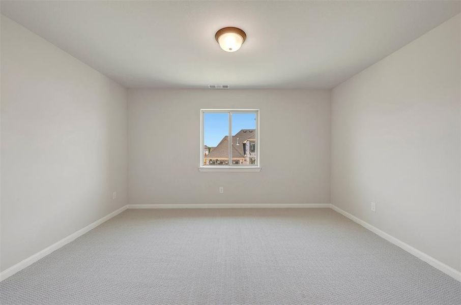 Neutral-toned interior room featuring light gray carpeting, white baseboards, and a single window with white trim