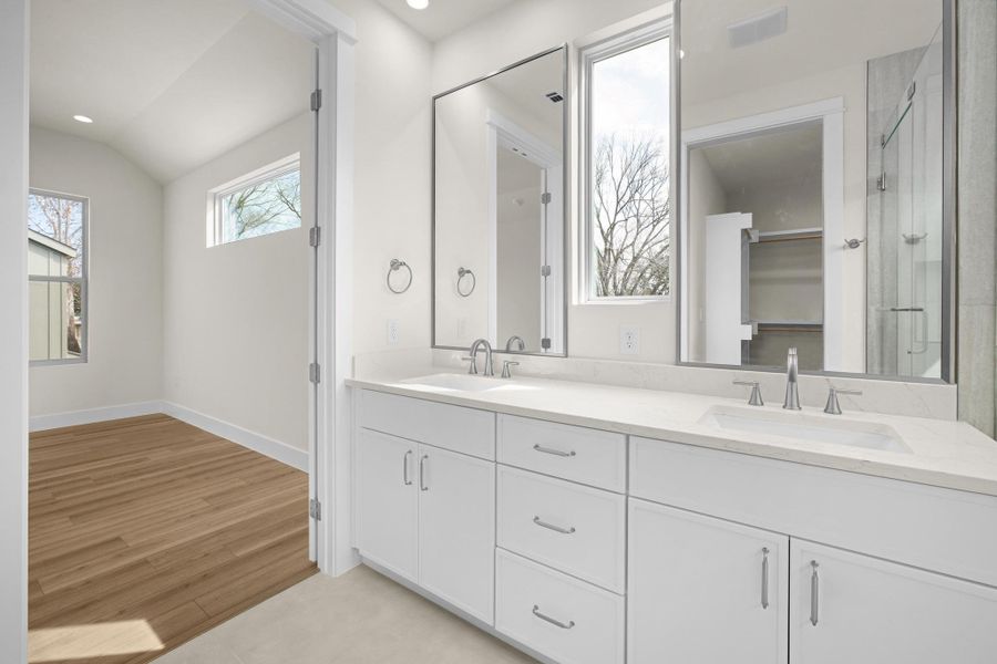 Full bath featuring double vanity, quartz countertop, lofted ceiling, LED lighting, tile flooring