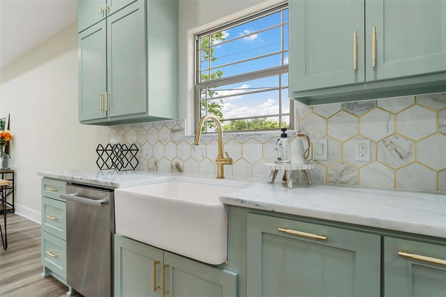 Kitchen featuring green cabinets, stainless steel dishwasher, a sink, and decorative backsplash