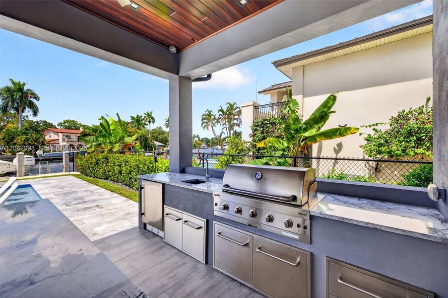 Outdoor kitchen w/ built in grill, refrigerator, ice maker and sink