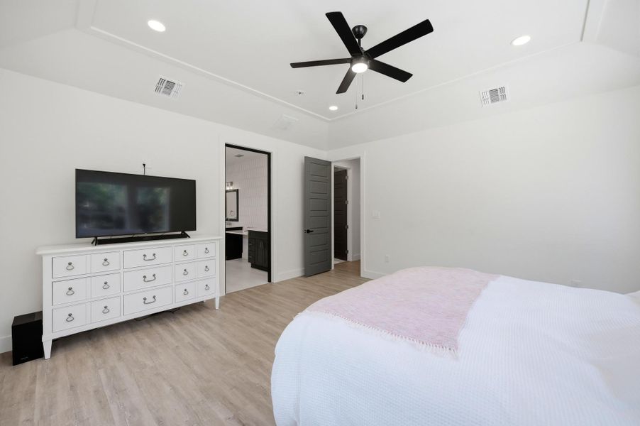 Recessed lighting and warm wood-style flooring elevate this modern bedroom.
