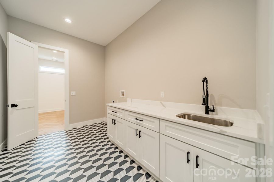 The fabulous Laundry Room boasts gorgeous tilework, custom cabinetry and sink.