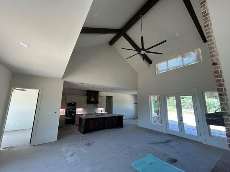 Spacious living area featuring a vaulted ceiling with exposed wood beams, a large ceiling fan, and recessed lighting